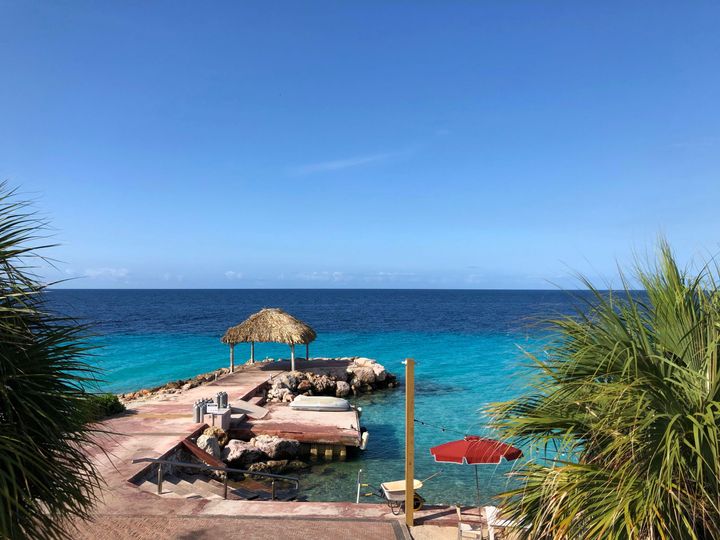 Crystal Blue ocean with a pier and sun umbrella at Karakter Beach Lounge, Curaçao
