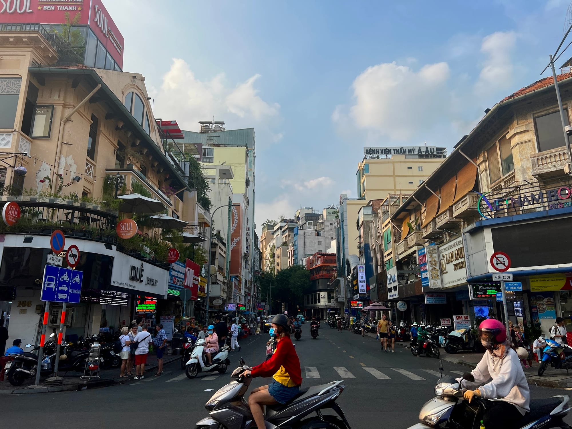 Busy streets of Ho Chi Minh City, people on motorbikes, shops, high buildings